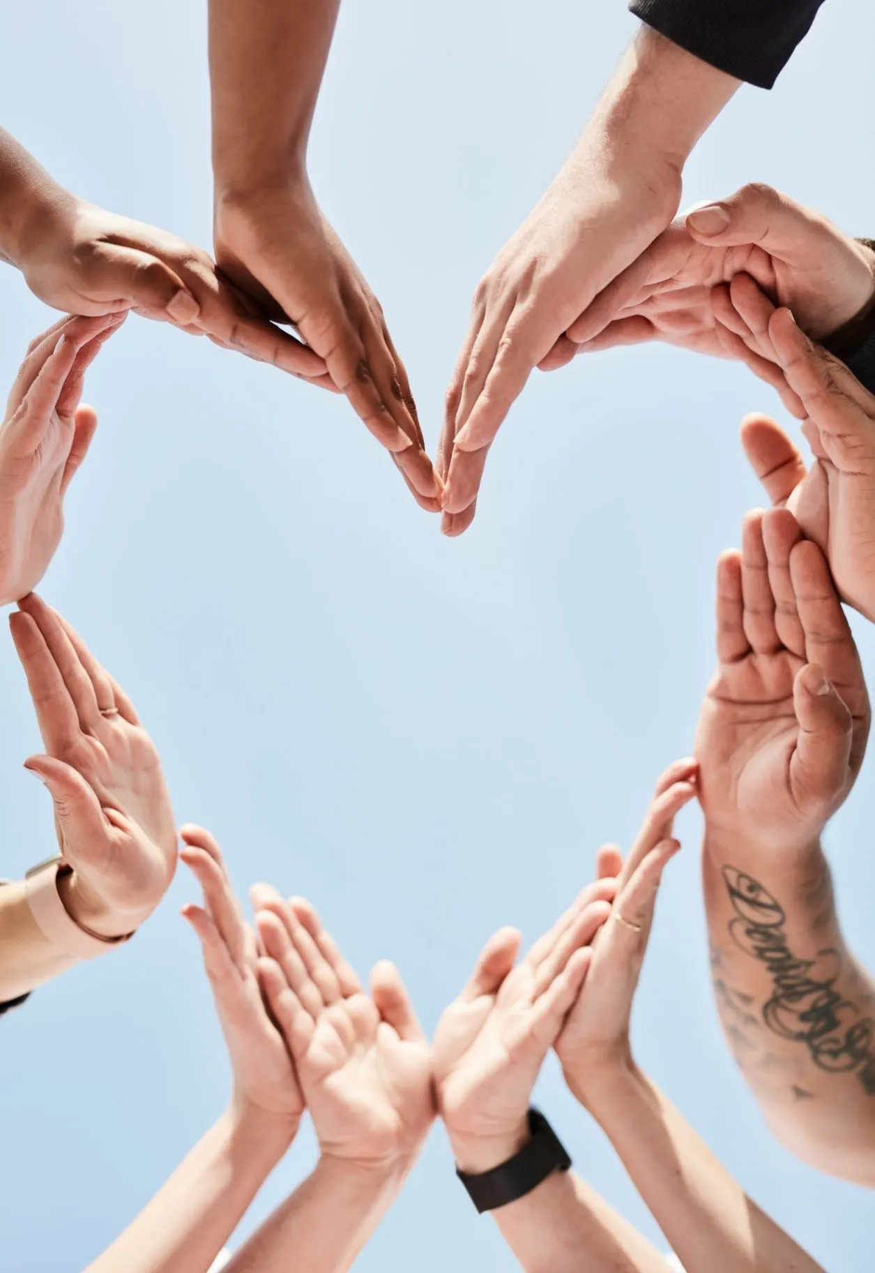 Hands forming a heart against a clear blue sky