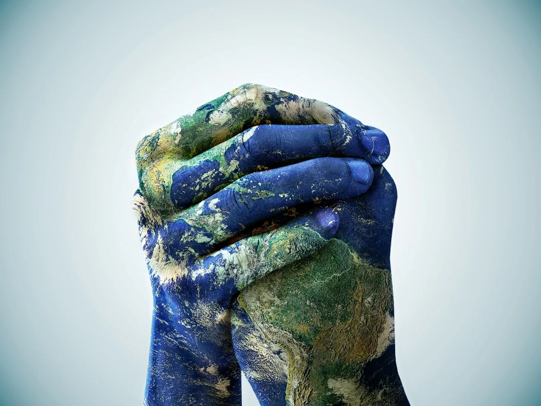 Hands clasped around a globe painted in blue and green